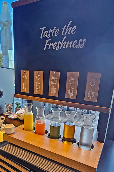 Juice station at breakfast of Hotel Jama, Postojna, Slovenia, with a displayed message "Taste the Freshness"; photo by Ivan Kralj.