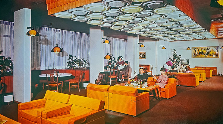 Retro-style ambient of Hotel Jama's lounge/restaurant in the 1970s, with orange furniture and guests enjoying conversations; photo from the hotel's archive, Postojna, Slovenia.