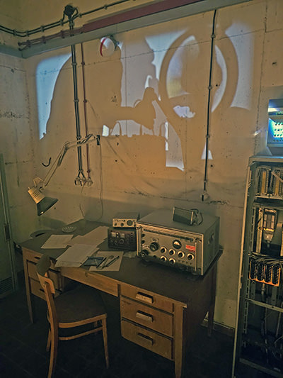 Radio and recording equipment displayed in Secret Rooms of Hotel Jama, Postojna, Slovenia, with projections of secret agents' shadows on the wall; photo by Ivan Kralj.