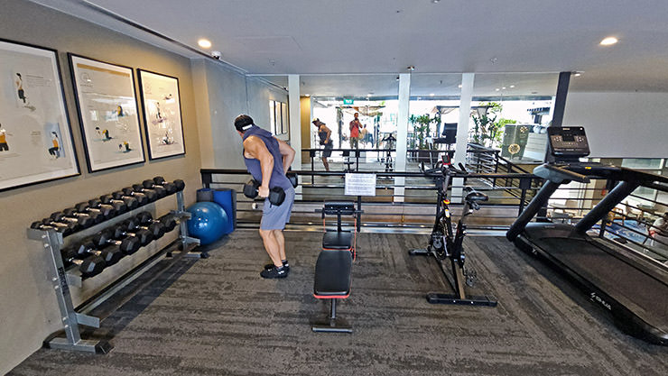 A man lifting weights in a small gym adjacent to the rooftop swimming pool at Singapore Changi Airport's Aerotel transit hotel; photo by Ivan Kralj.