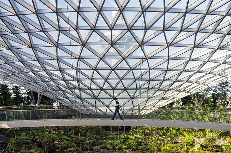 A man walking over the Canopy Bridge in Jewel, Changi's sky dome; photo by SaMaN, Unsplash.