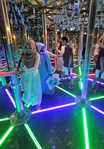 People having fun in the neon-lighted Mirror Maze, a part of the Canopy Park, theme park at the top level of Jewel Changi Airport in Singapore; photo by Ivan Kralj.