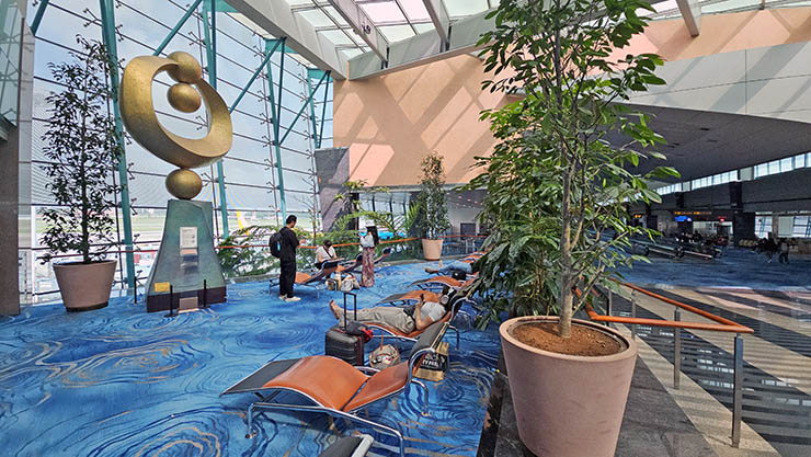 Passengers resting near Ng Eng Teng's sculpture "Success", part of "The Spirit of Man" artwork installed at Terminal 1 of Singapore Changi Airport; photo by Ivan Kralj.